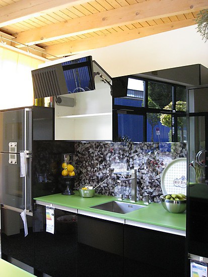 Schwarze Design Ausstellungskueche mit Oberschraenken und gemusterter Glasrückwand